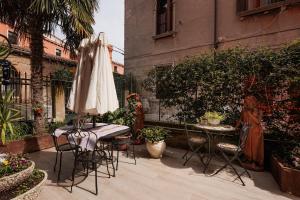 un patio con sombrilla, mesa y sillas en Appartamento Luxury Ai Greci, en Venecia