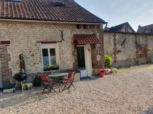 a table and chairs in front of a brick house at Charmante maison au bord des falaises in Les Authieux-sur-le-Port-Saint-Ouen