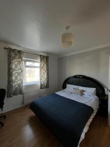 a bedroom with a large bed with a blue blanket at Charlton, Greenwich Luxury Self Check-in Rooms in London