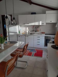 a kitchen with white cabinets and a table and chairs at Dünenhaus NADINE in De Haan