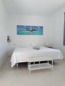 a white bedroom with a white bed and a painting at Casa tomas C in Villaverde