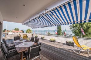 a deck with a table and chairs and an umbrella at Hotel am Yachthafen in Konstanz