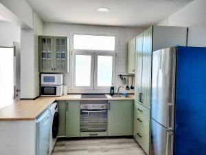 cocina con armarios verdes y nevera azul en Parisito Sancti Petri, en Chiclana de la Frontera