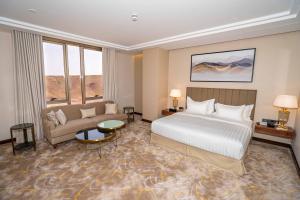 ShaqraにあるLe Bosquetのベッドとソファ付きの広いホテルルームです。