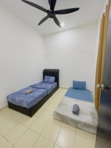 2 Betten in einem Zimmer mit Deckenventilator in der Unterkunft Anaqi Homestay Tawau Sabah in Kampong Parit