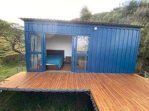 a blue shed with a bed on a deck at Hotel Campestre los Duraznos in Cucunubá