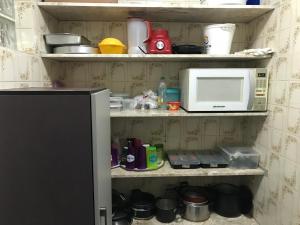 a kitchen shelf with a microwave and other kitchen items at Beach House Ocean in Bertioga