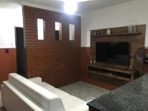 a living room with a brick fireplace and a television at Beach House Ocean in Bertioga