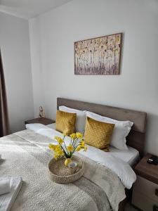 Un dormitorio con una cama con un jarrón de flores. en Tei Residence, en Piatra Neamţ