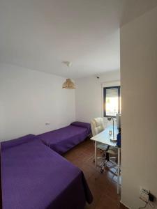 a bedroom with purple beds and a table and a desk at Apartamento en Las Negras in Las Negras