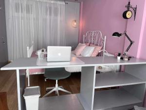 - un bureau blanc avec un ordinateur portable dans une chambre rose dans l'établissement Retro House with Garden in Anopoli, à Thessalonique