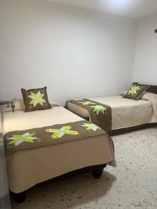 2 bedden in een kamer met 2 bedden, waarvan 1 tweepersoonsbed en 1 eenpersoonsbed. bij Acojedora y comoda in Cali
