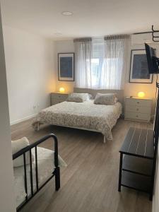 a bedroom with two beds and a table and a window at Mata Beach Caparica in Costa da Caparica