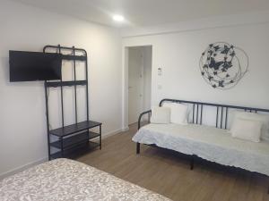 a bedroom with two beds and a flat screen tv at Mata Beach Caparica in Costa da Caparica