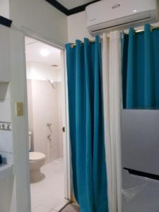 y baño con cortina de ducha azul y aseo. en Budget 2 bedrooms near airport, en Lapu Lapu City