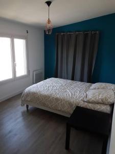 ein Schlafzimmer mit einem Bett und einer blauen Wand in der Unterkunft Maison tout confort à Saint-Michel-Chef-Chef in Saint-Michel-Chef-Chef