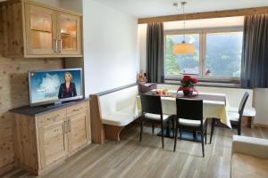 eine Küche und ein Esszimmer mit einem Tisch und einem TV in der Unterkunft Apartments La Mana in St. Christina in Gröden