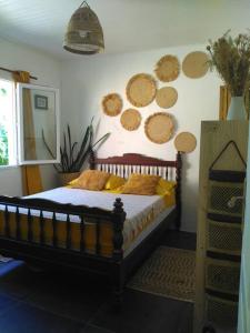 1 dormitorio con 1 cama y algunos platos en la pared en La petite case jaune , jaccuzi pierre à 3 min à pied du bassin Manapany, vue mer, en Saint-Joseph
