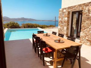 Agios Georgios的住宿－Luxurious Villa Antiparos，一个带游泳池的庭院里的一张木桌和椅子