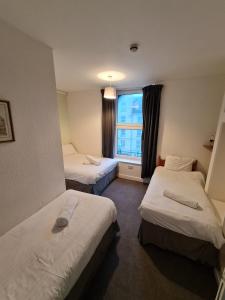 a hotel room with three beds and a window at Farina No6, Sea view apartment sleeping 4 guests in Bridlington