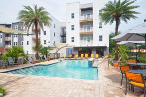 uma piscina num hotel com mesas e cadeiras e palmeiras em Luxe One Bedroom Apartment with Balcony em Gainesville