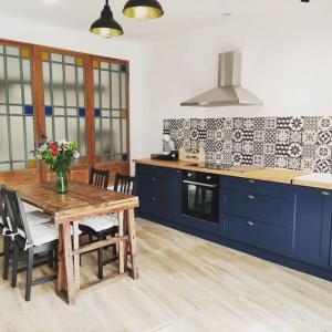 cocina con mesa de madera y armarios azules en Gîte de l'atelier, en Saint-Privat