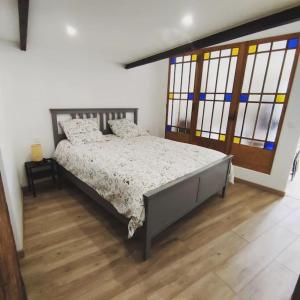 a bedroom with a bed with a wooden floor and windows at Gîte de l'atelier in Saint-Privat