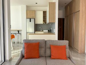 sala de estar con sofá y 2 almohadas de color naranja en Mojito Beach Apartments with Free Parking, en Sarandë