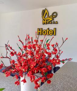 un jarrón blanco con flores rojas delante de un cartel de hotel en MARIA HOTEL, en Ba Tri