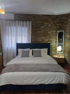 a large bed in a bedroom with a brick wall at Bella Gaia in Eleftheroúpolis