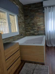 a bath tub in a bathroom with a stone wall at Bella Gaia in Eleftheroúpolis