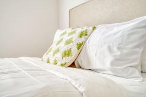 ein weißes Bett mit weißen Laken und einem Kissen in der Unterkunft Deluxe One Bedroom Apartment in Gainesville