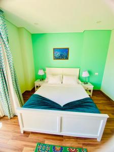 a bedroom with a white bed with green walls at Tiba Rose hurghada in Hurghada