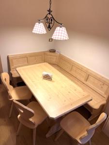 uma mesa de jantar em madeira com cadeiras e 2 luzes em EMARGHE, CASA A MOENA em Moena