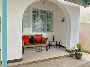 um alpendre com um sofá com almofadas vermelhas e uma mesa em Homely apartments 4 em Kisumu