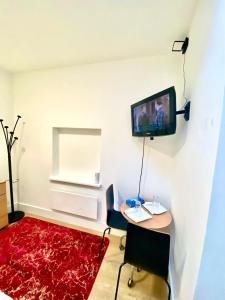 um quarto com uma mesa e uma televisão na parede em Lovely Cosy Studio Apartment Ground Floor In Central London em Londres
