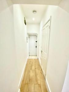um corredor vazio com uma porta branca e um piso de madeira em Lovely Cosy Studio Apartment Ground Floor In Central London em Londres