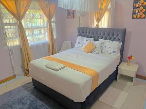 um quarto com uma cama grande e 2 janelas em Homely apartments 4 em Kisumu