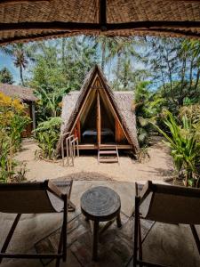 a tent with a table and two chairs in front of it at Basa-basi Lodge in Karimunjawa