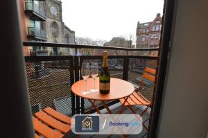 a table with two glasses and a bottle of wine on a balcony at LGI Stunning 1 Bedroom Apartment By Movida Property Group Short Lets & Serviced Accommodation in Leeds
