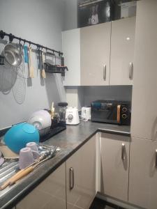 a kitchen with white cabinets and a counter top at SEYI in Hatch End