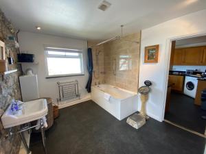 a bathroom with a bath tub and a sink at HUER'S WATCH a beautifully presented PRIVATE APARTMENT with far reaching VIEWS Over ST IVES HARBOUR and BAY and FREE ONSITE PARKING for LARGER GROUPS book along with our Connecting TWO SISTER APARTMENTS in St Ives +12 photos