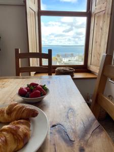 una mesa con un plato de pan y un bol de fruta en HUER'S WATCH a beautifully presented PRIVATE APARTMENT with far reaching VIEWS Over ST IVES HARBOUR and BAY and FREE ONSITE PARKING for LARGER GROUPS book along with our Connecting TWO SISTER APARTMENTS, en St Ives