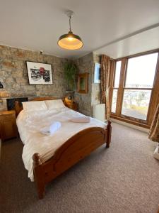 a bedroom with a large bed with a stone wall at HUER'S WATCH a beautifully presented PRIVATE APARTMENT with far reaching VIEWS Over ST IVES HARBOUR and BAY and FREE ONSITE PARKING for LARGER GROUPS book along with our Connecting TWO SISTER APARTMENTS in St Ives