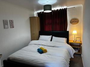 ein Schlafzimmer mit einem weißen Bett mit einem gelben Objekt darauf in der Unterkunft Marton Apartments in Marton