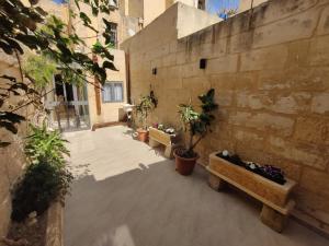 an empty courtyard with two benches and potted plants at Peaceful Traditional Maltese Townhouse in Luqa