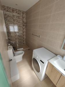 a bathroom with a washing machine and a toilet at Peaceful Traditional Maltese Townhouse in Luqa