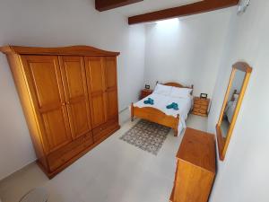 a bedroom with a bed and a wooden cabinet at Peaceful Traditional Maltese Townhouse in Luqa