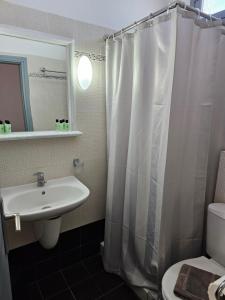 ein Badezimmer mit Waschbecken und Duschvorhang in der Unterkunft Hotel Leta in Fira + 28 Fotos