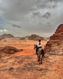 un hombre montando un caballo en el desierto en Tamim Luxury Camp, en Wadi Rum